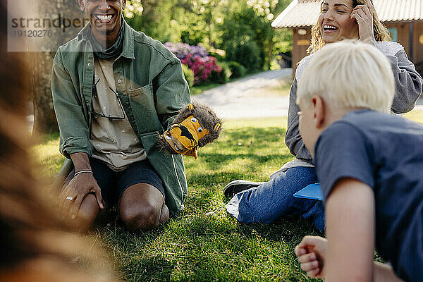 Betreuer spielen mit den Kindern  während sie im Sommercamp im Gras sitzen