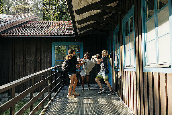Fröhliche Kinder spielen mit Kissen im Korridor neben der Hütte im Ferienlager