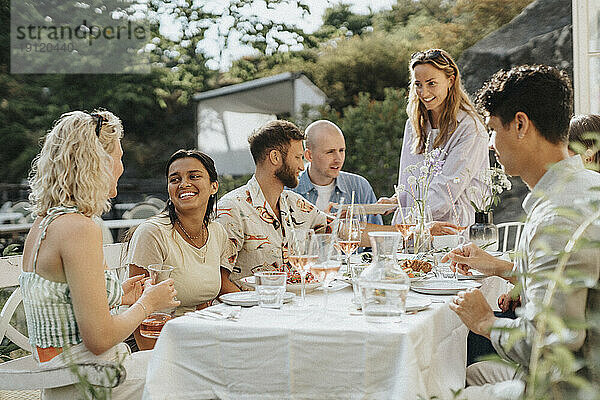 Glückliche männliche und weibliche Freunde  die das Essen genießen  während sie eine Dinnerparty im Café feiern