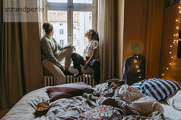 Junge Freundinnen sitzen am Fenster im Schlafzimmer