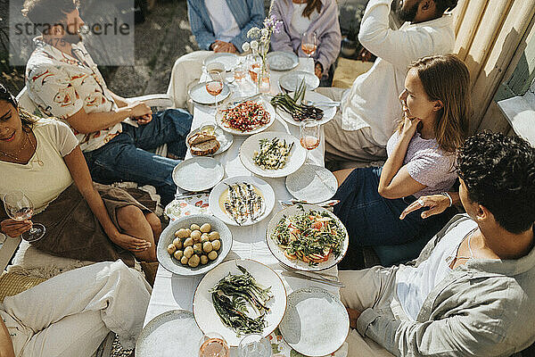 Hohe Winkel Ansicht der männlichen und weiblichen Freunde genießen das Essen während des Abendessens Partei im Café