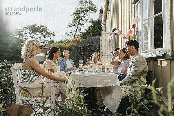 Männliche und weibliche Freunde unterhalten sich während einer Dinnerparty im Café