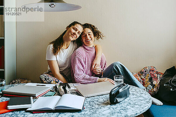 Porträt von glücklichen jungen Freundinnen  die zu Hause sitzen