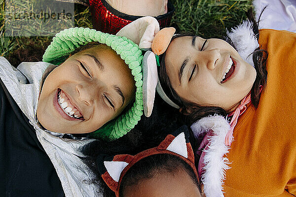 Unbekümmerte Kinder mit geschlossenen Augen  die lachend auf dem Rasen im Ferienlager liegen