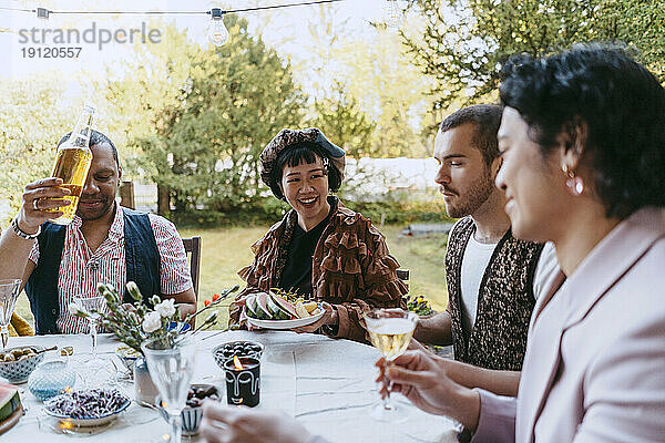 Glückliche Freunde aus der LGBTQ-Gemeinschaft genießen Wein bei einer Dinnerparty im Hinterhof