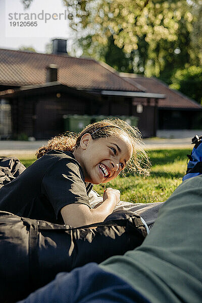 Seitenansicht eines glücklichen Mädchens  das lachend im Sommercamp liegt