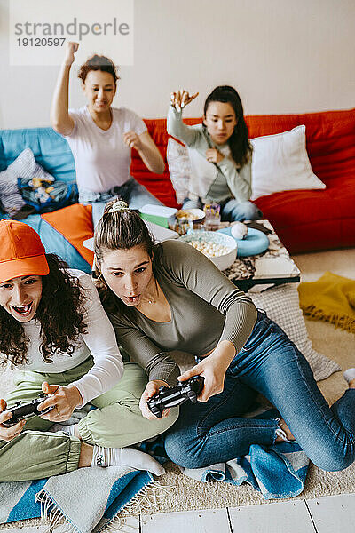 Fröhliche junge Freundinnen spielen ein Videospiel zu Hause
