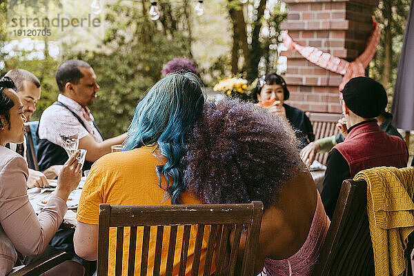 Rückansicht von LGBTQ-Freunden  die während einer Dinnerparty im Hinterhof zusammensitzen
