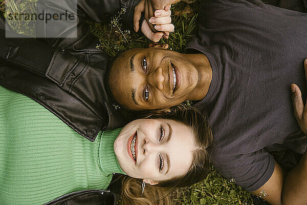 Direkt über der Ansicht einer glücklichen jungen Frau und eines Mannes  die im Gras liegen