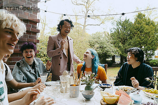 Fröhliche Freunde der LGBTQ-Gemeinschaft  die sich bei einer Dinnerparty im Hinterhof amüsieren