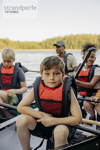 Porträt eines Jungen  der eine Schwimmweste trägt  während er im Kajak im Sommerlager sitzt