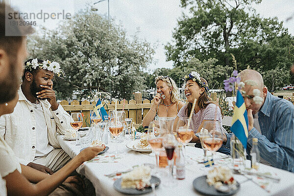 Glückliche multirassische männliche und weibliche Freunde  die während einer Dinnerparty im Café feiern