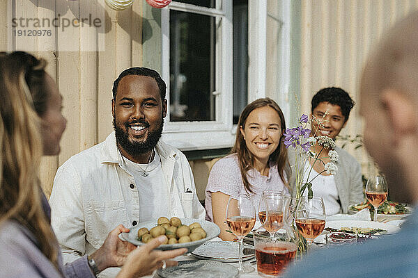 Frau serviert männlichen und weiblichen Freunden Babykartoffeln während einer Dinnerparty im Cafe