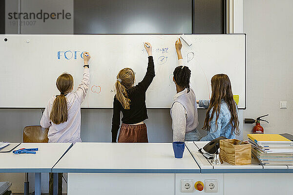 Studentinnen schreiben im Klassenzimmer auf die Tafel