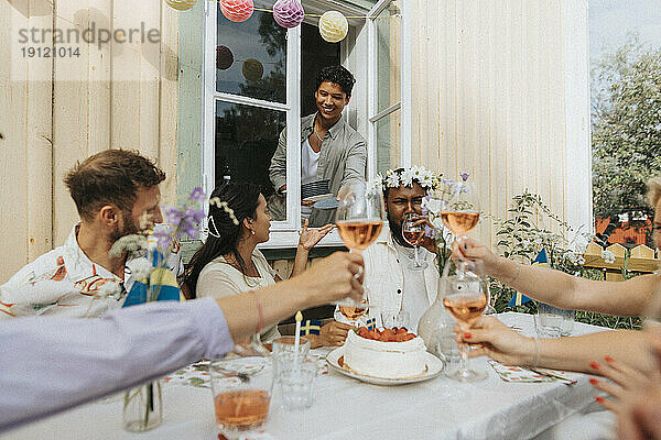 Lächelnde männliche und weibliche Freunde  die eine Party feiern und vor einem Café sitzen