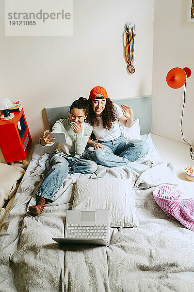 Glückliche Freundinnen  die zu Hause über ihr Smartphone Videoanrufe tätigen