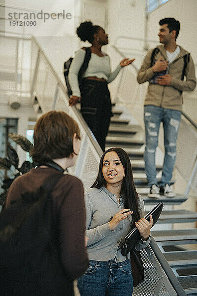 Multirassische Studentinnen diskutieren im Treppenhaus einer Universität