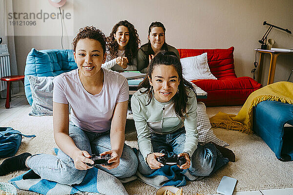 Glückliche Freundinnen spielen ein Videospiel im Wohnzimmer zu Hause