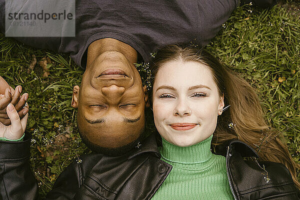 Direkt über der Ansicht einer lächelnden jungen Frau und eines Mannes  die im Gras liegen