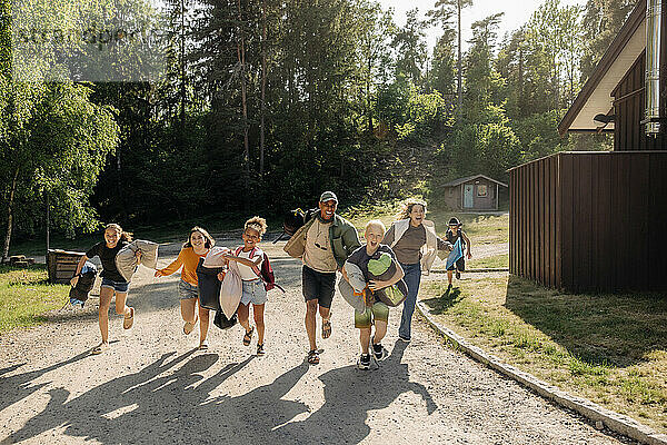 Glückliche Kinder laufen mit Betreuern auf dem Fußweg im Sommercamp