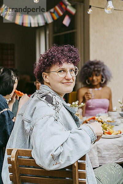 Porträt einer lächelnden nicht-binären Person während einer Party im Hinterhof