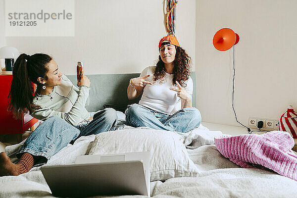 Junge Frau fotografiert ihre Freundin mit dem Smartphone zu Hause