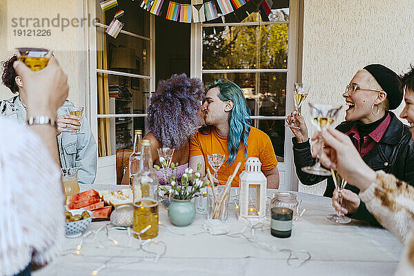 Romantische Transfrau küsst schwulen Freund während einer Dinnerparty im Hinterhof
