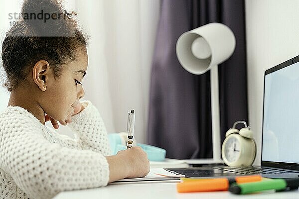 Seitenansicht kleines Mädchen in der Onlineschule zu Hause mit Laptop