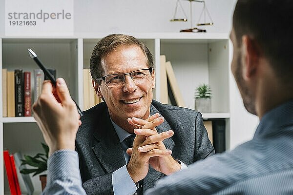 Porträt reifer glücklicher Anwalt mit Klient sitzend