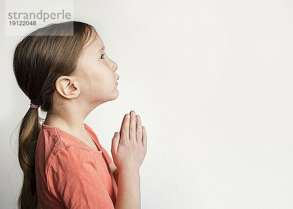 Schönes kleines Mädchen betet mit Kopierraum