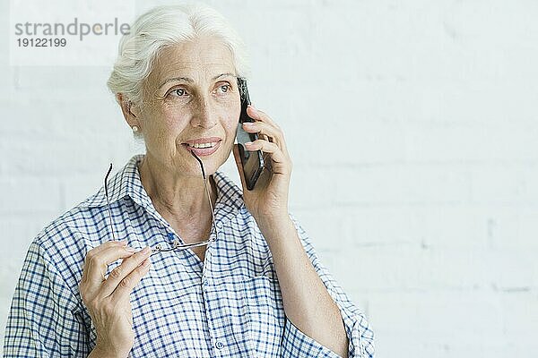 Porträt einer lächelnden älteren jungen Frau  die mit einem Mobiltelefon spricht