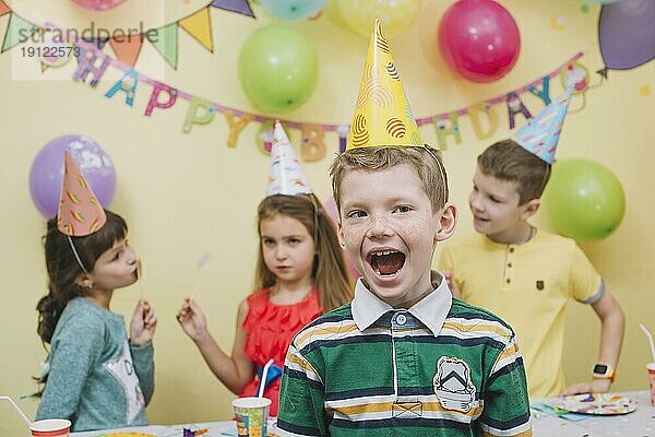 Fröhlicher Junge  der mit Freunden Geburtstag feiert