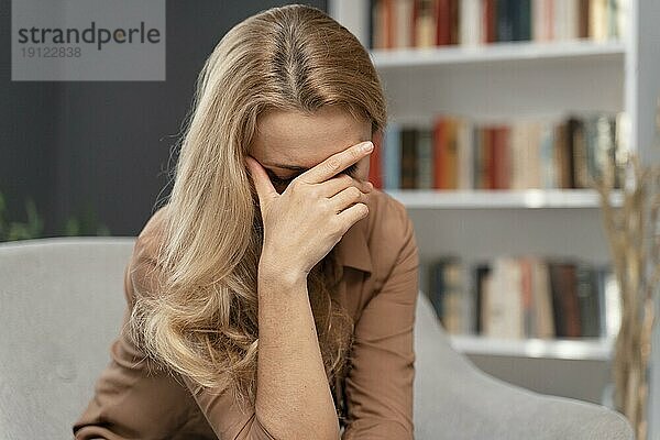 Blonde Frau bedeckt Gesicht mit Hand