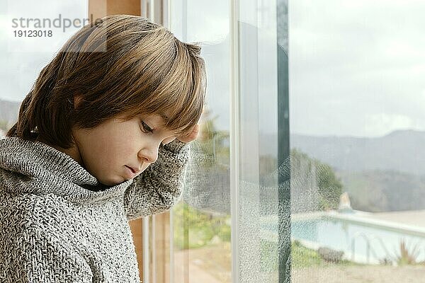 Seitenansicht trauriger Junge am Fenster stehend