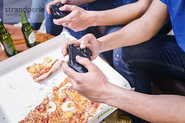 Freunde essen Pizza und spielen Konsole