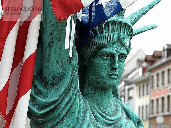 Figur der Freiheitsstatue mit US-Flagge  Hintergrund Häuser  aufgenommen mit Tiefenschärfe