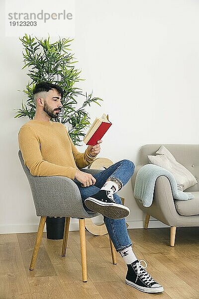 Seitenansicht gut aussehend ernster junger Mann sitzt Stuhl lesen Buch