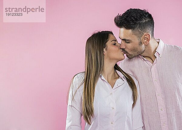 Junges Paar küsst rosa Hintergrund