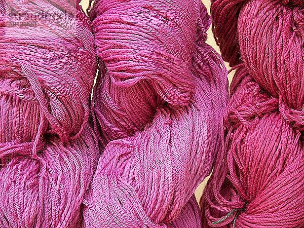 Drei rosafarbene Wollknäuel in unterschiedlichen Farbschattierungen
