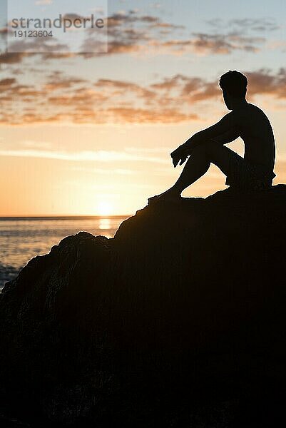 Mann entspannt am Strand bei Sonnenuntergang