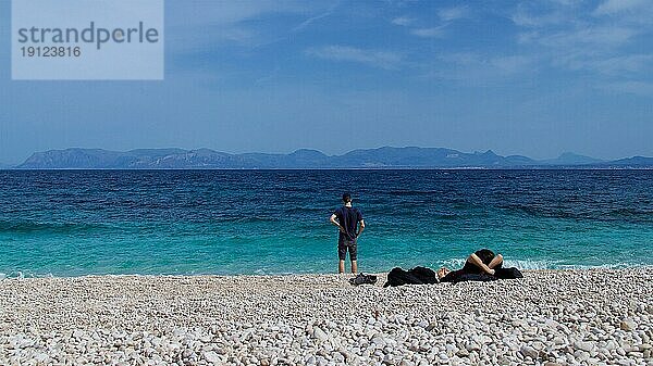 Kiesstrand  Türkisfarbenes Meer  Küstenlinie  Mensch steht am Strand  Mensch liegt auf dem Strand  von hinten  Zingaro  Nationalpark  Naturschutzgebiet  Nordwesten  Sizilien  Italien  Europa
