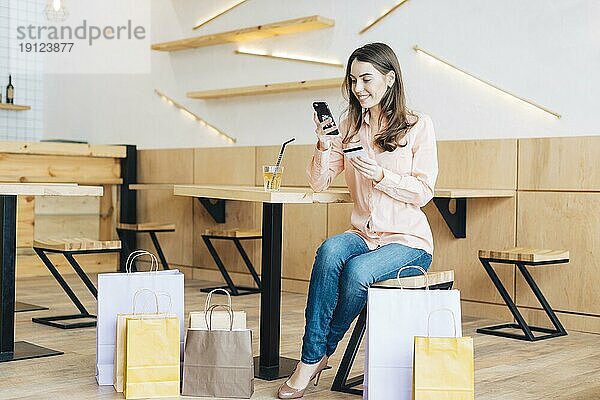 Frau mit Kreditkarte und Smartphone in einem Café