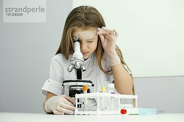 Frontansicht neugieriges junges Mädchen Wissenschaftlerin mit Mikroskop