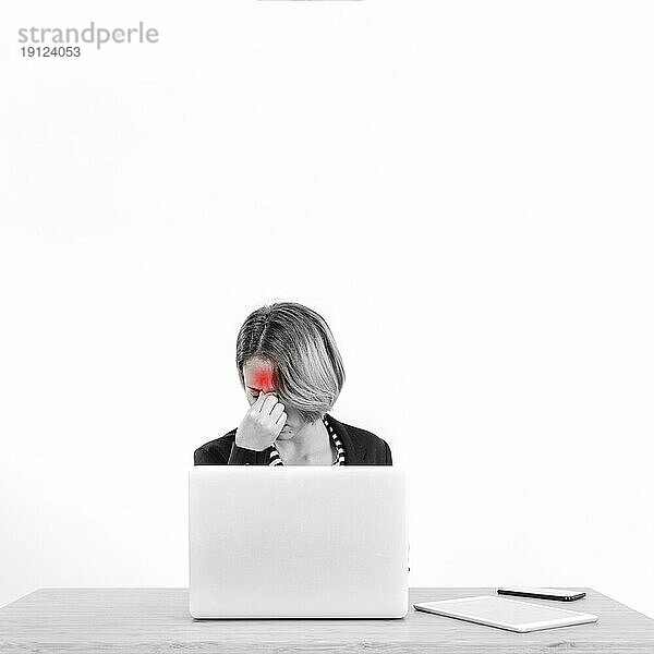Frau mit Kopfschmerzen bei der Arbeit am Laptop