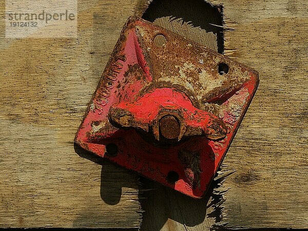 Eiserner rot angestrichener  leicht angerosteter Spannanker  an einer Holzwand befestigt