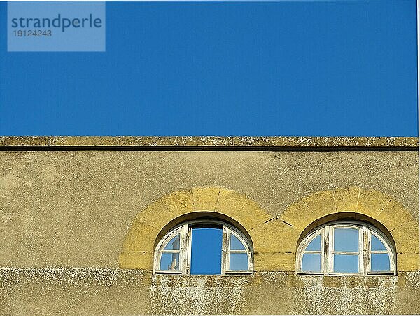 Oberer Teil eines alten Gebäudes mit einem geöffneten und einem geschlossenen Fenster  Hintergrund blaür Himmel