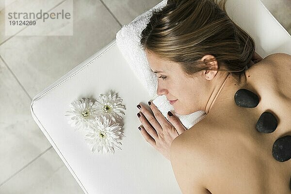 Hohe Winkel Ansicht junge Frau liegend Bett erhalten heißen Stein Massage