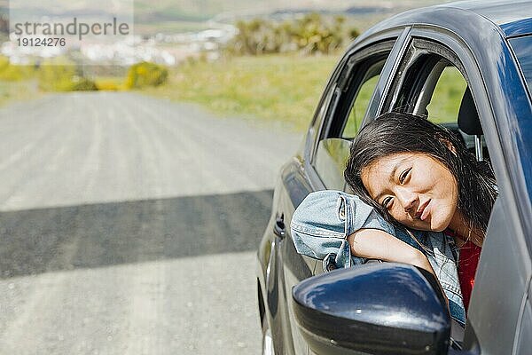 Lächelnde asiatische Frau schaut aus dem Auto