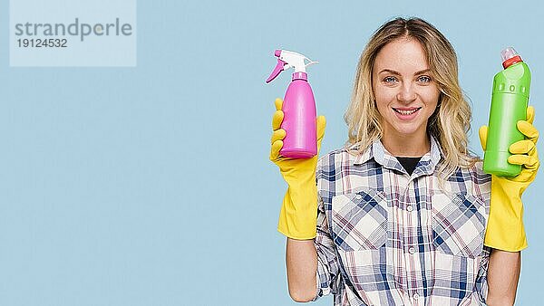 Vorderansicht glückliche Frau mit Blick in die Kamera hält Sprühflasche Waschmittelflasche