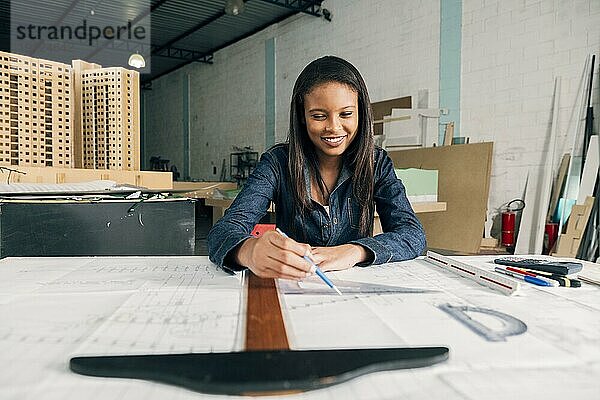 Glückliche afroamerikanische Dame mit großem Lineal Stift Tisch